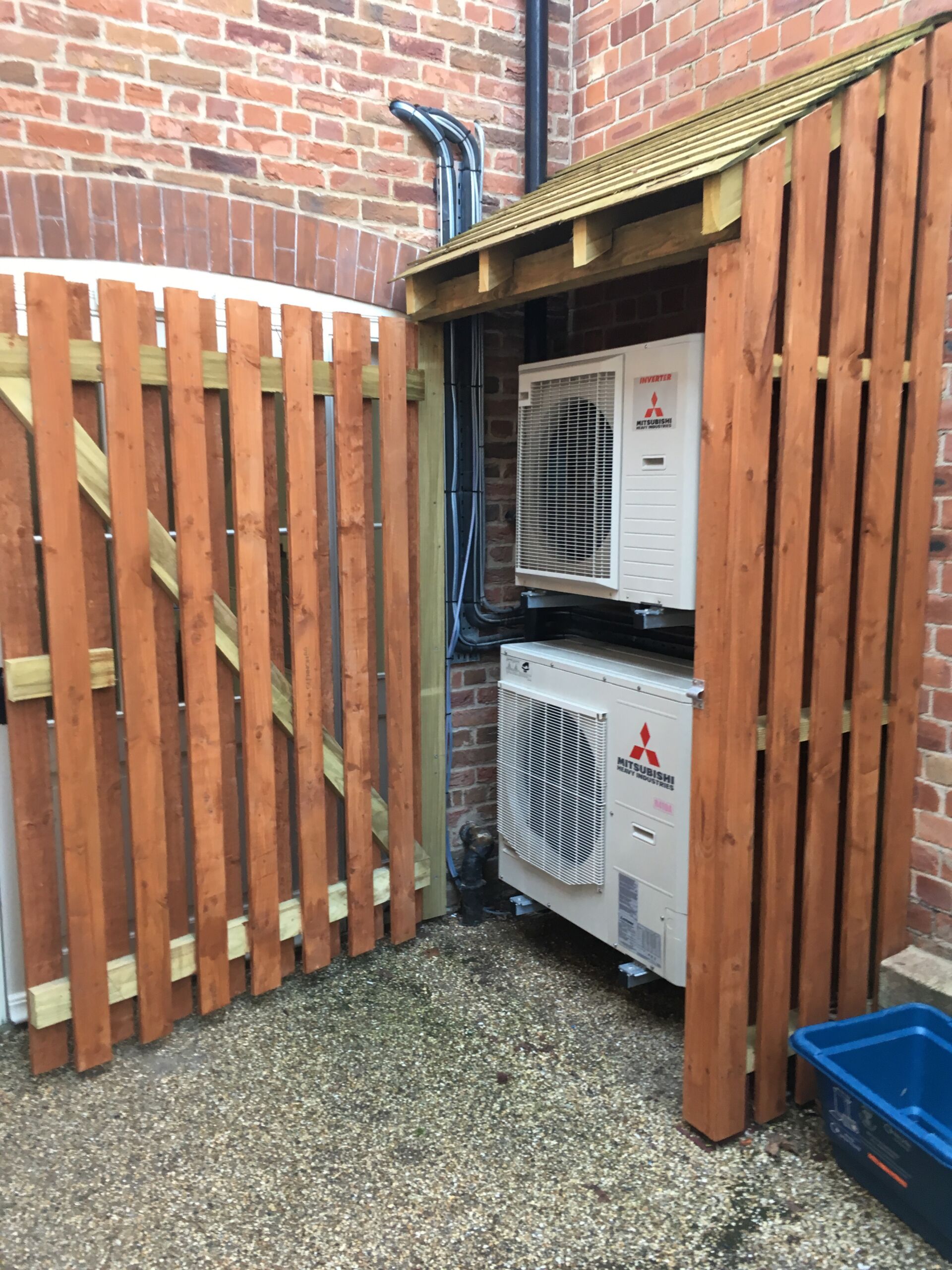 2 air conditioning units installed on a wall in a wooden protective box